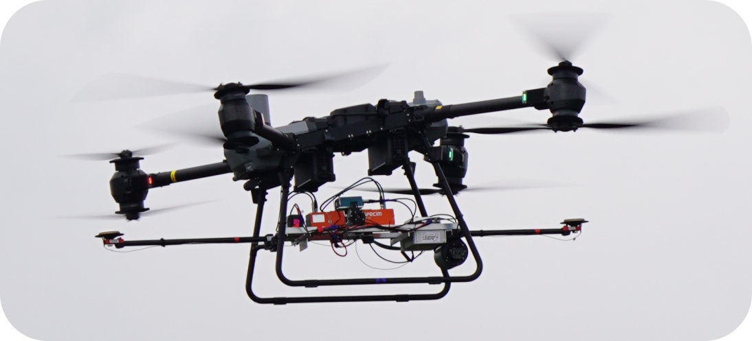 Large multi-rotor drone with visible wiring and sensors flying against an overcast sky.