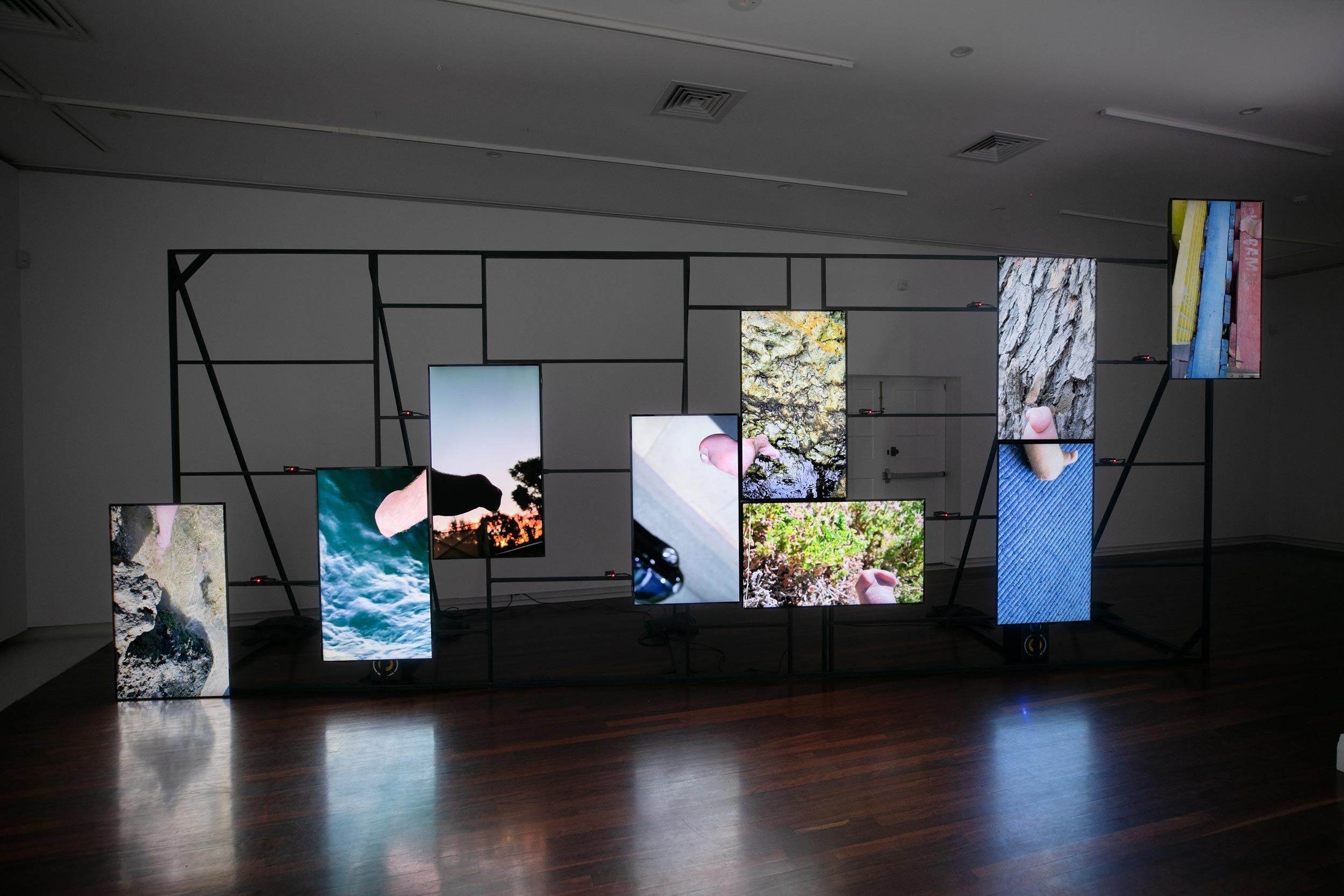 image shoes 9 large screens mounted to a thin black frame, each screen depicts a different scene 