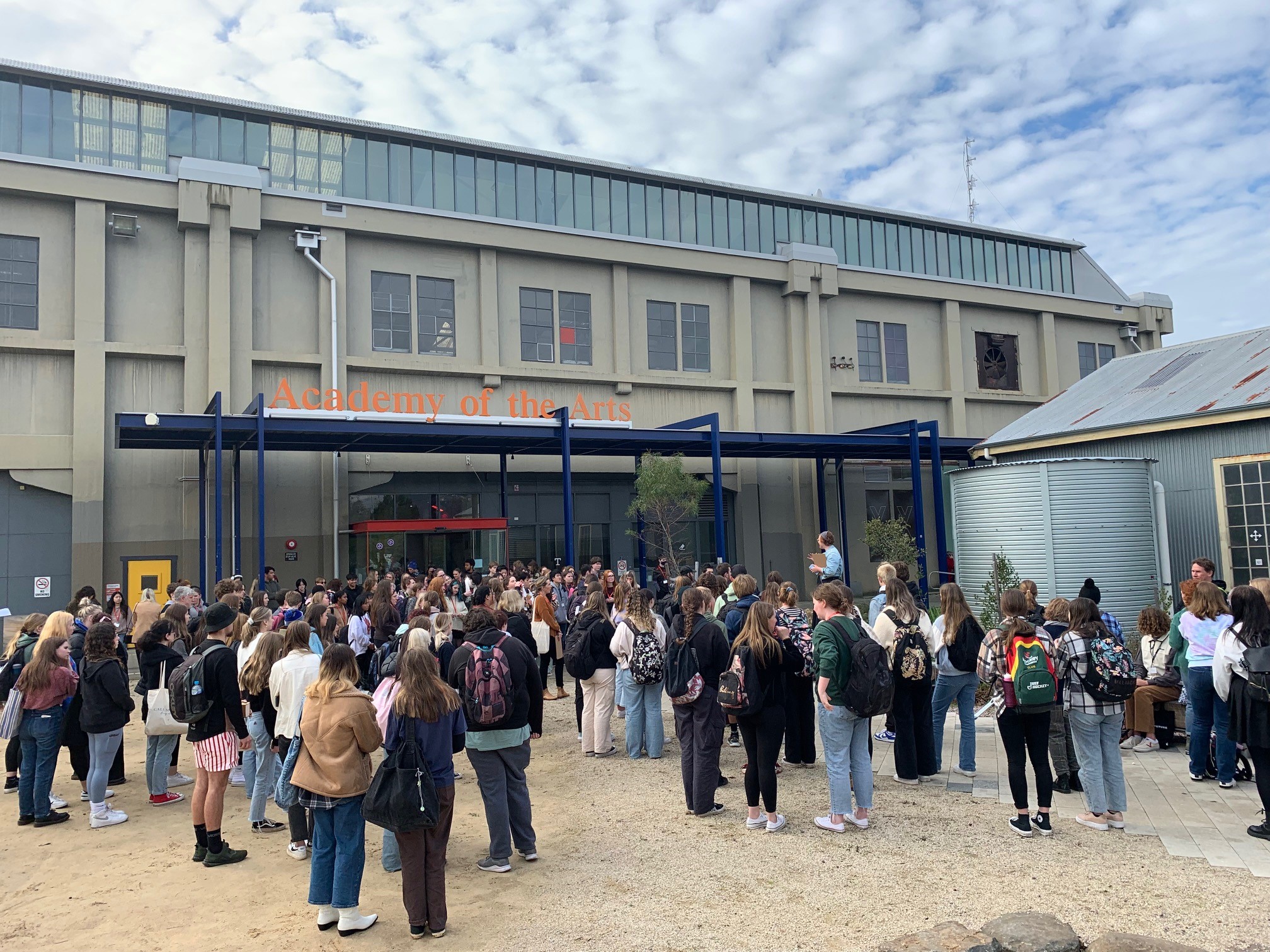A large group of secondary school students gather outside the 'Academy of the Arts' building at the University of Tasmania's Inveresk campus
