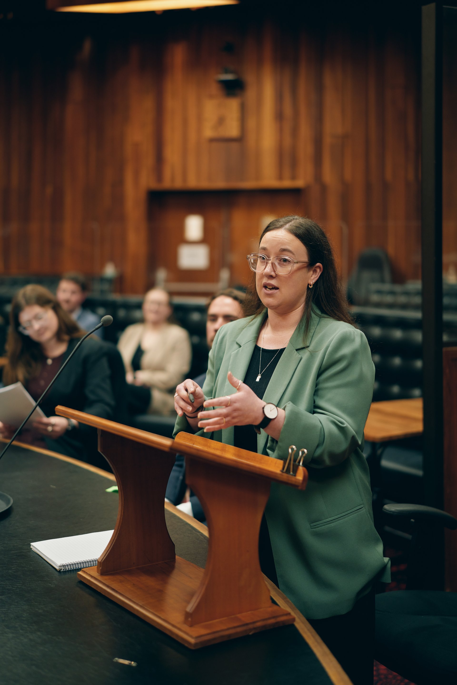Woman in a green jacket addressing the judge