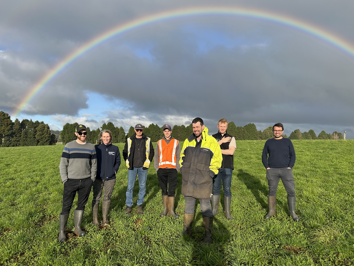 TIA and Dairy Australia team members standing in paddock with rainbow in the sky.