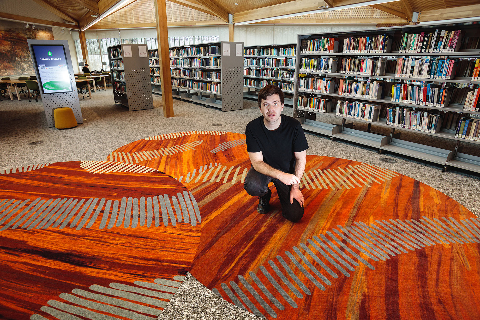 Caleb Nichols-Mansell with artwork carpets, Inveresk Library. Credit: Kelly Slater