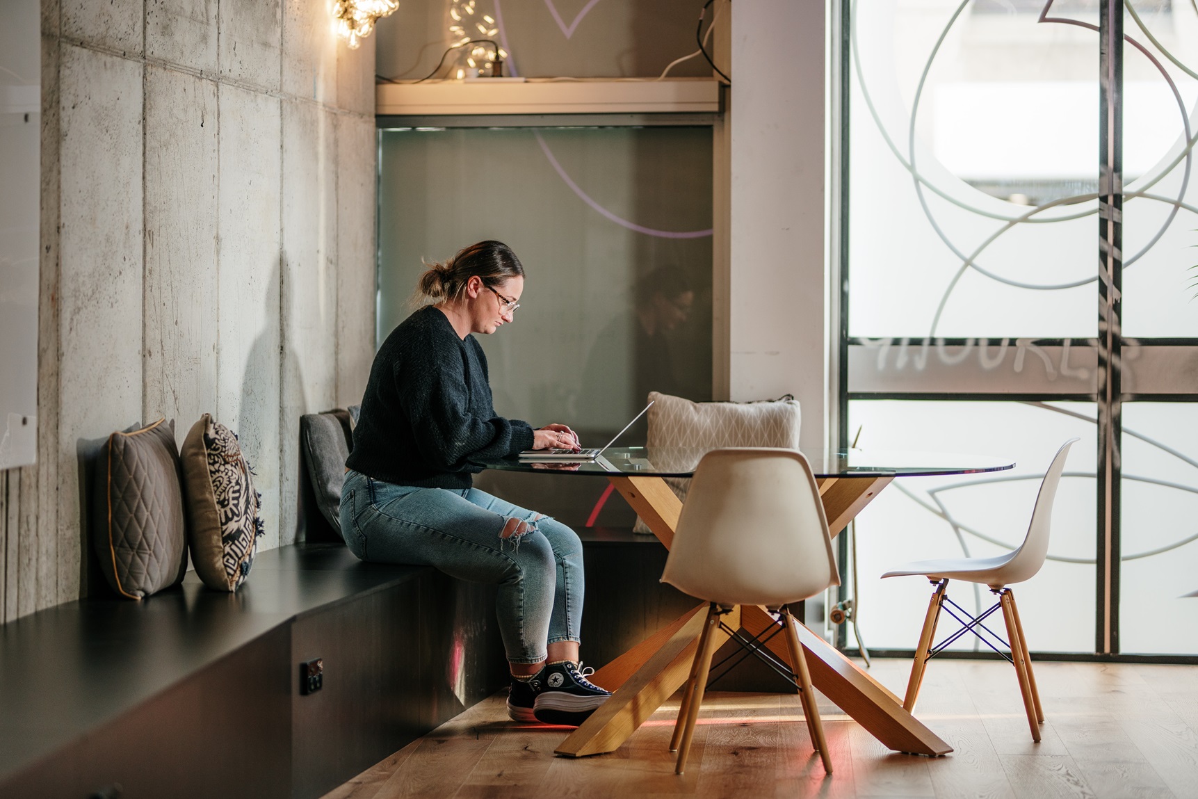 University of Tasmania Bachelor of Business graduate Georgie Daly sits working at a table in the offices of Launceston marketing and design agency S. Group. (Picture supplied by S. Group)