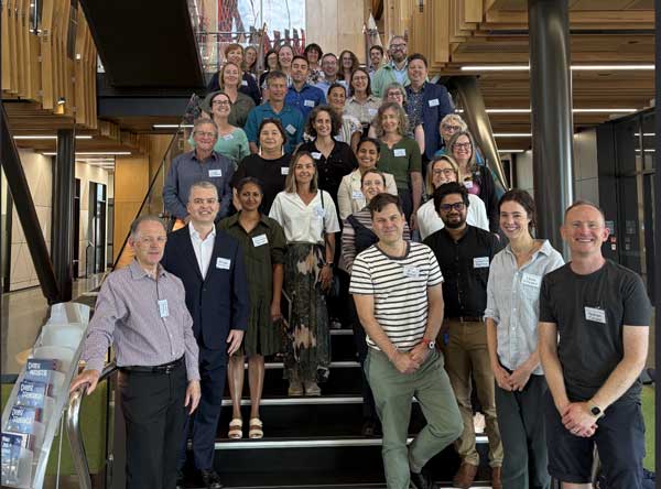A group of attendees from the Frontiers of Environmental Law Colloquium 2025 gather on a staircase, smiling and posing for a group photo