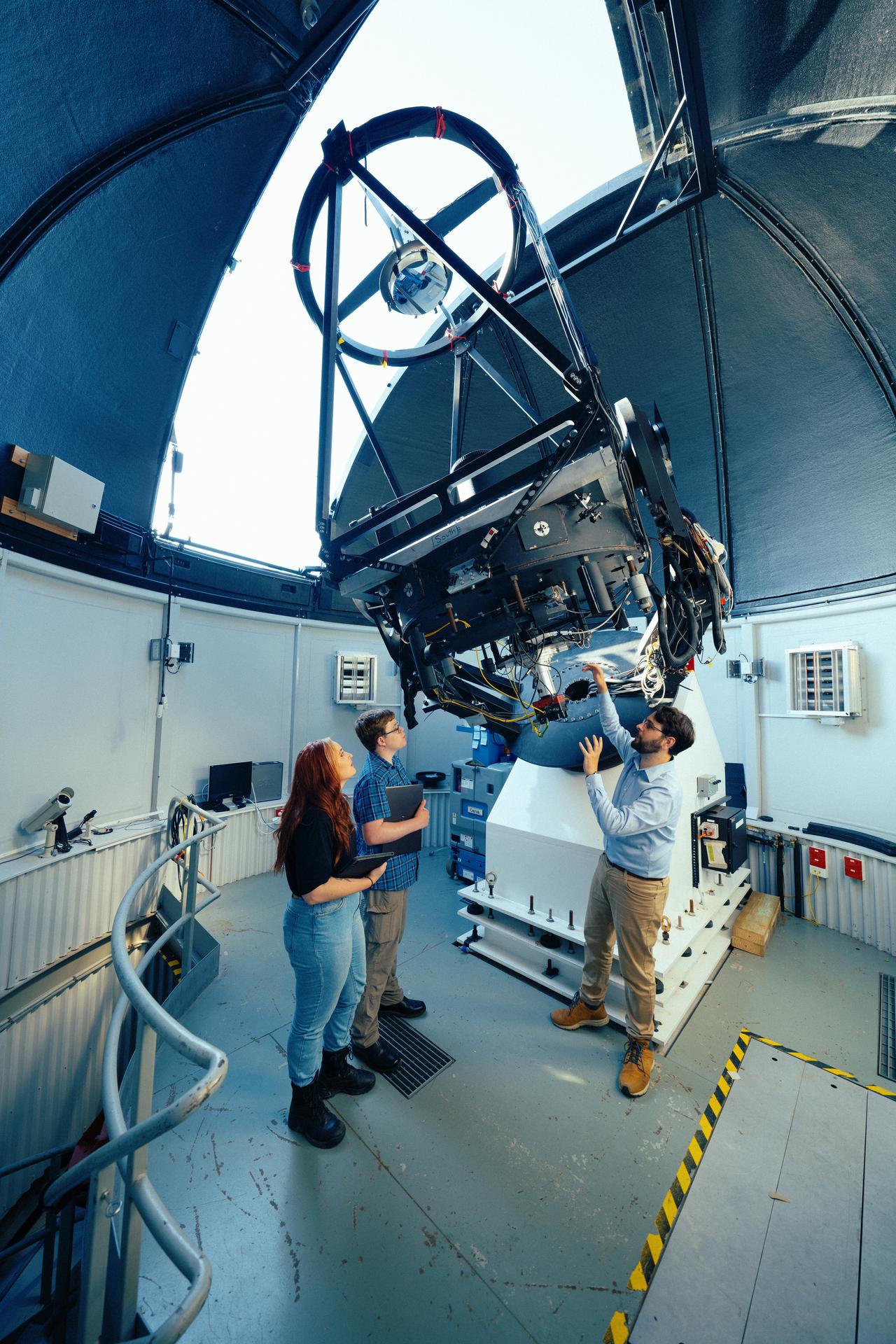 Physics students Morgan Febey and Oliver White take a close look at one of the optical telescopes at Greenhill Observatory with telescope technical officer Bryn Emptage.