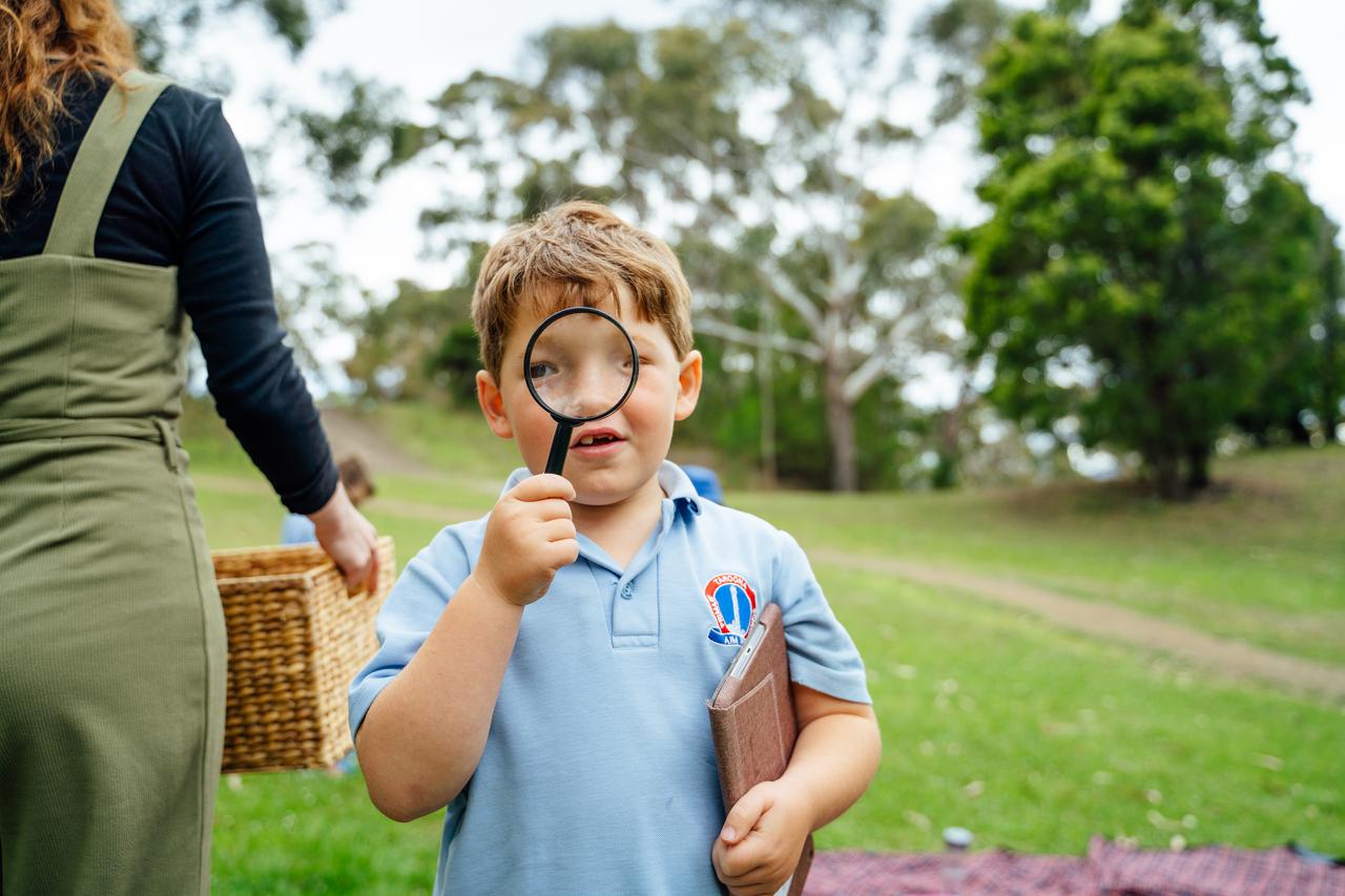Student in park with magnifying glass