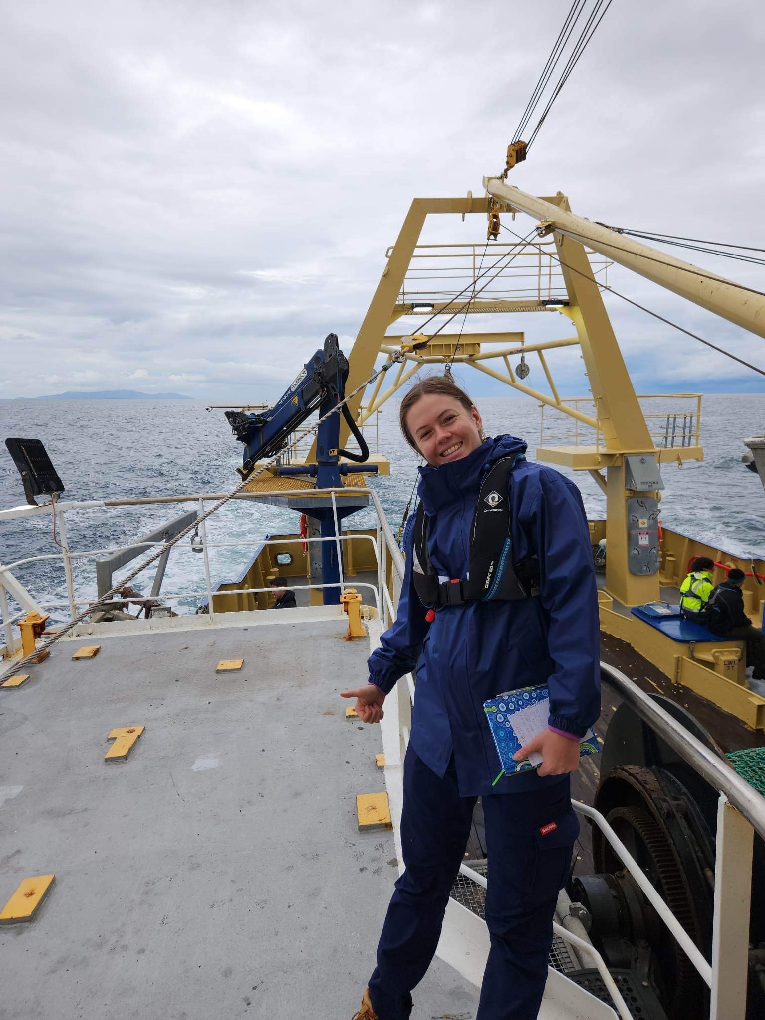 Bachelor of Maritime Engineering student Cameron Skeggs in foul-weather gear, on the deck of a ship, out on the water during one of her hands-on naval architecture assignments.