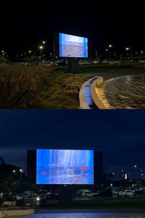Outdoor screen at night with parked cars and starry sky.