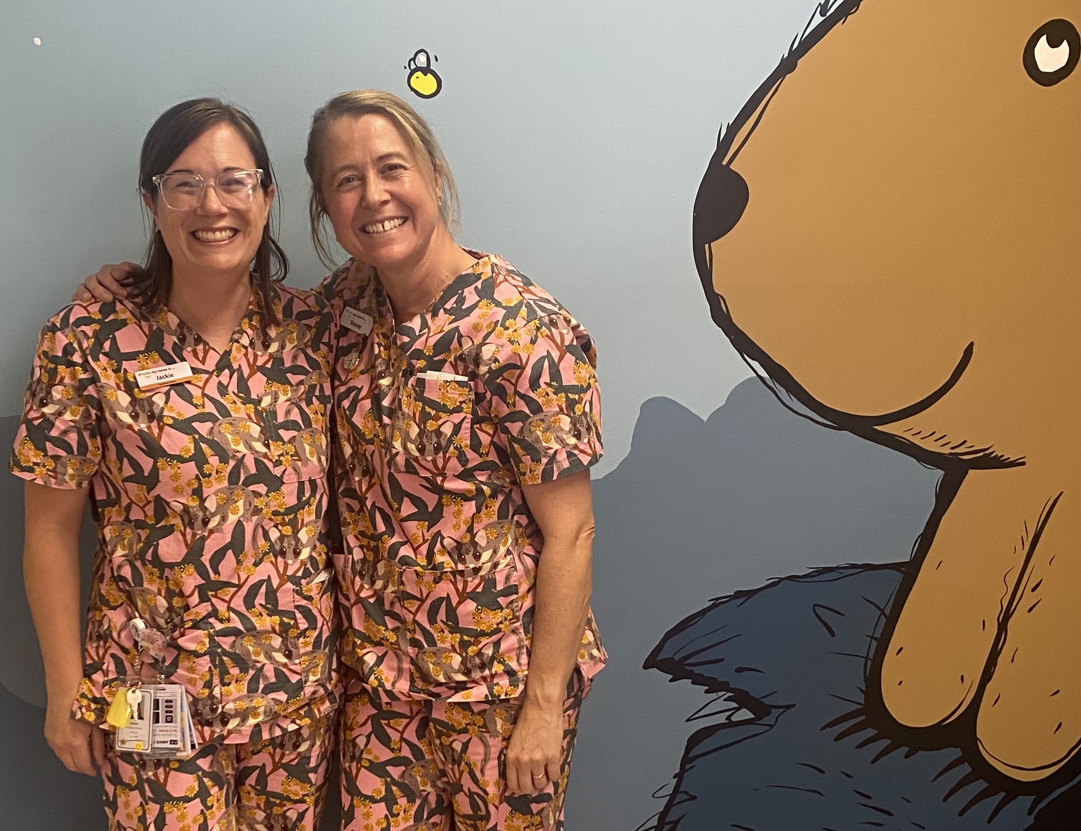 Nurses Jackie and Stacey wearing colourful scrubs and smiling