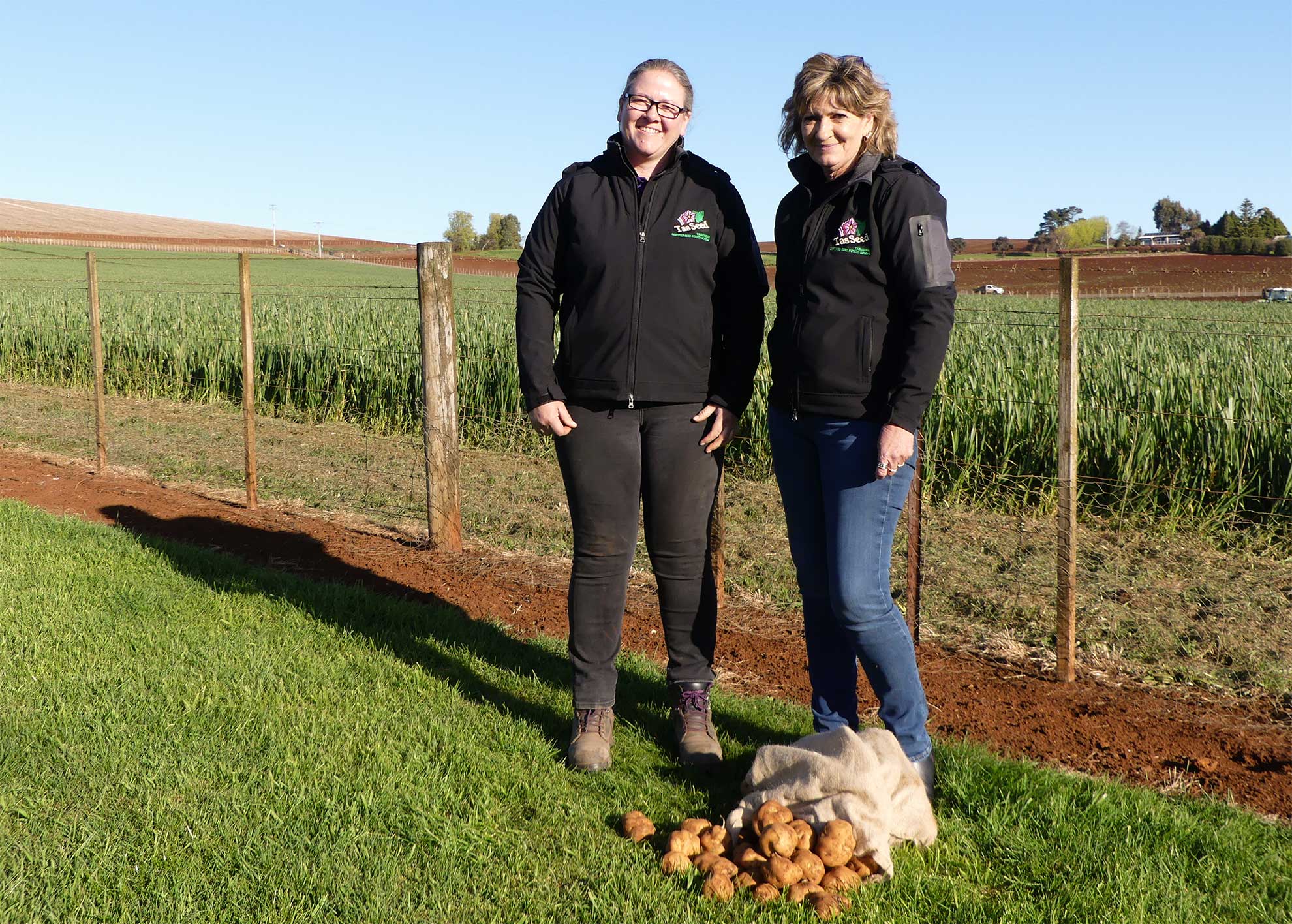Tasmanian Certified Seed Potato Scheme Certification Officers, Kathryn Goulding and Ann-Maree Donoghue, standing with a bag of potatoes.