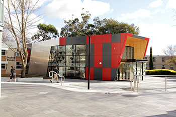 Contemporary entrance with glass doors and red geometric pattern on external walls