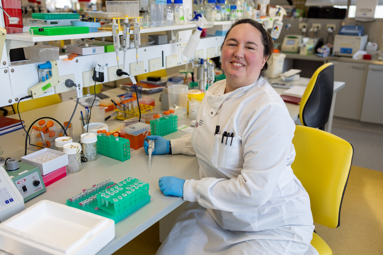 Person wearing a lab coat sitting at a laboratory bench