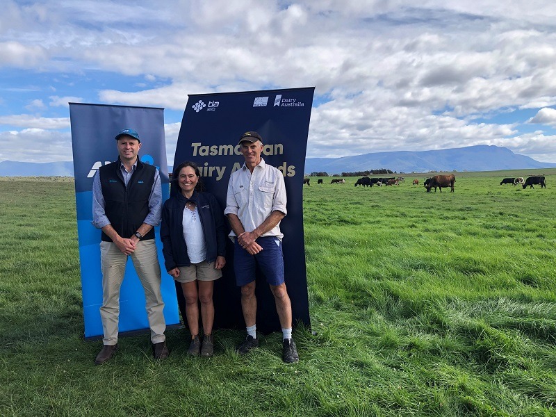 Janefield Dairy's Brian and Michele Lawrence with ANZ's Rick Webb. They all stand in front of banners in a paddock at Cressy.