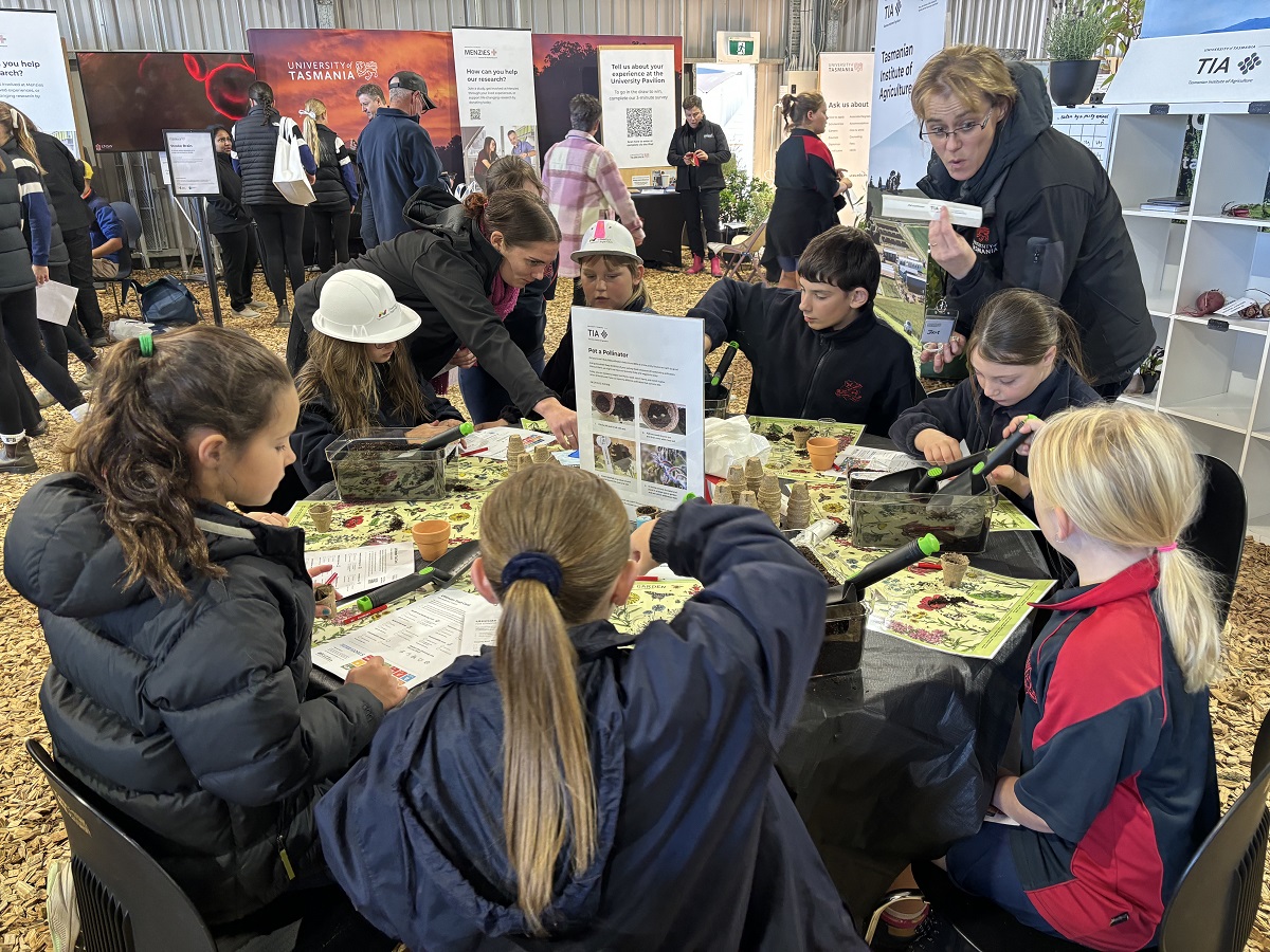 Young students sitting around a round table filling pots with soil and seeds 