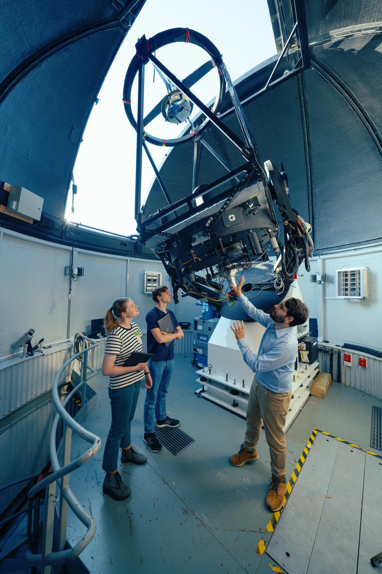Physics students Matilda Downes Smolenski and Euan Hamdorf take a close look at one of the optical telescopes at Greenhill Observatory with telescope technical officer Bryn Emptage.